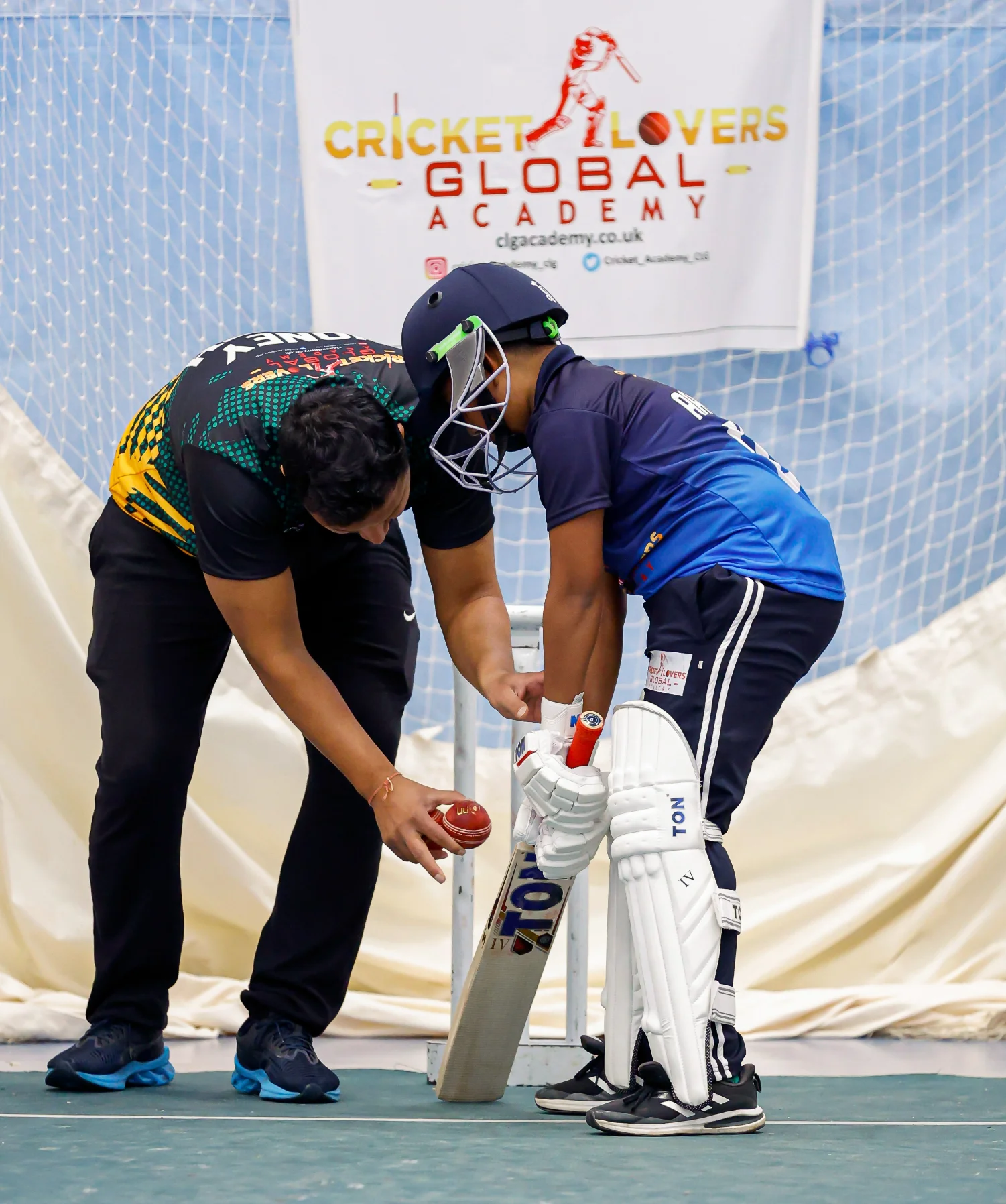 cricket coach helping player with bat
